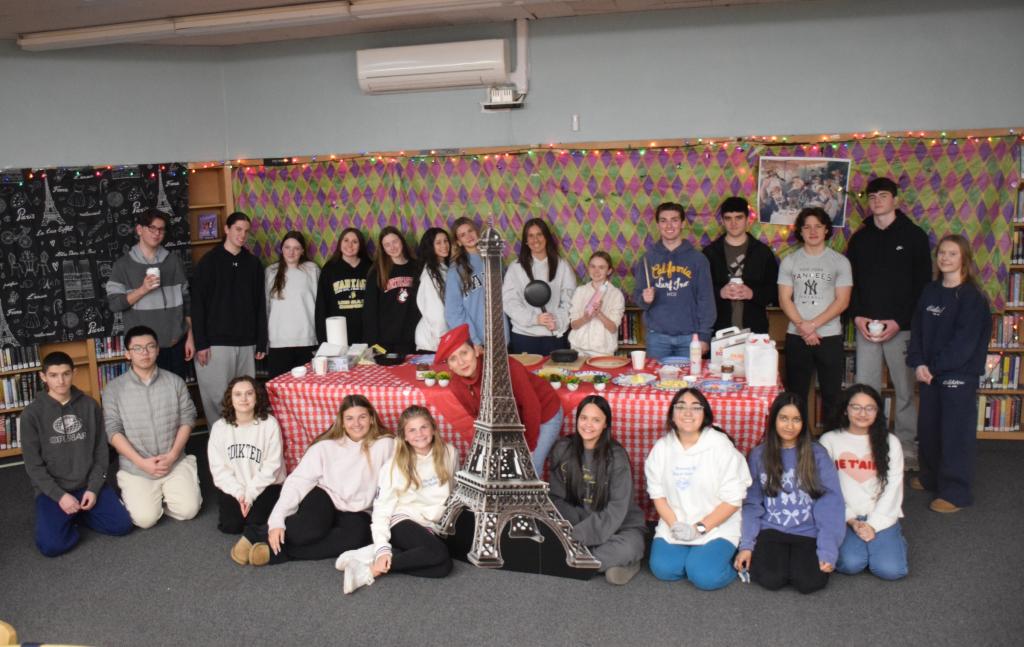 students smiling around small version of eiffel tower